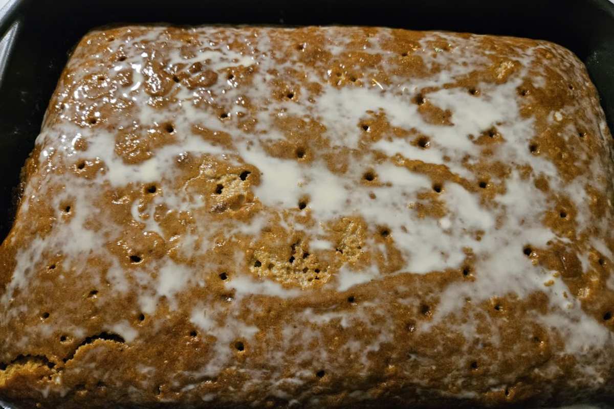 Poking holes into a pumpkin cake, with tres leches milk mixture being poured to soak the cake for extra moisture.